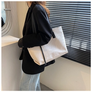Detail view of large white quilted tote bag with black contrast straps for women