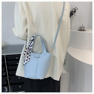 Light blue bucket bag detail with polka dot scarf handle and adjustable strap