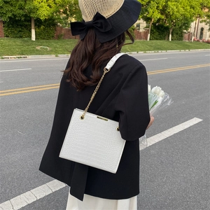 Sac bandoulière blanc rétro à motif crocodile avec chaîne dorée porté par un modèle
