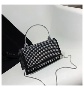 Close-up of elegant black rhinestone evening bag with silver metal handle and chain strap