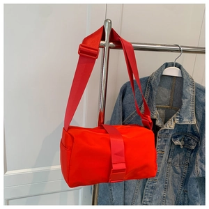 Dettaglio della borsa tote in nylon rosso con tracolla larga e design sportivo casual