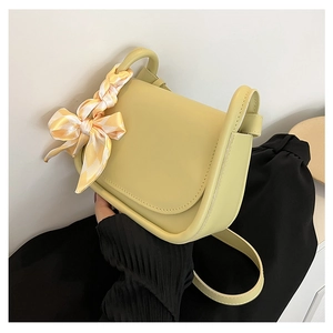 Detail of light green saddle bag featuring a decorative checkered scarf on handle