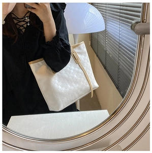 Detail of white woven checkerboard tote bag with beige leather trim and long shoulder strap