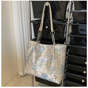 Detailed close-up of vintage tote bag featuring floral embroidery and chain strap