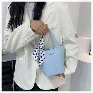 Detail of light blue leather bucket bag with a stylish polka dot silk scarf handle accent