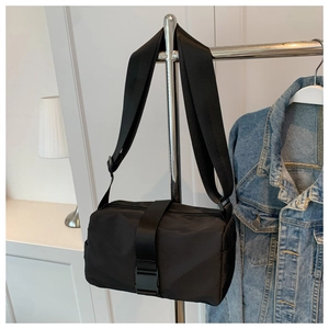Close-up of black nylon cylinder crossbody bag with adjustable wide strap and buckle