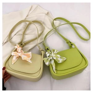 Detail showing cream and green faux leather saddle bags with decorative silk scarves