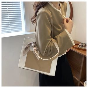 Detail of white woven tote bag with brown leather pocket and decorative silk scarf