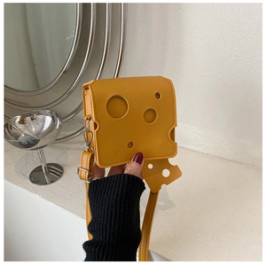 Détail du sac à bandoulière jaune en forme de fromage avec des trous et un pendentif