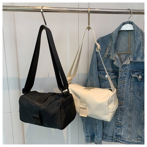 Detail of nylon cylinder crossbody bags in black and beige with wide woven straps