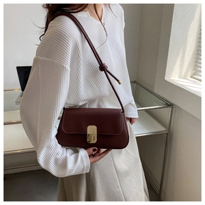 Model wearing dark brown vintage baguette bag with gold buckle and knotted strap detail