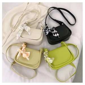 Minimalist mini saddle bags in four colors with decorative silk scarves on white fabric