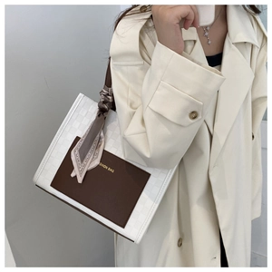 Detail of checkered tote bag featuring a leather pocket and decorative printed silk scarf