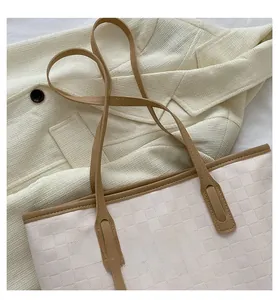 Detail of slim brown leather strap and beige checkered texture on a tote bag