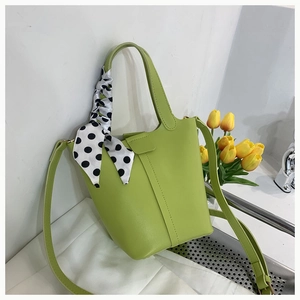 Detail view of lime green leather bucket bag featuring a polka dot silk scarf handle