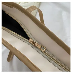 Close-up of golden zipper detail on beige faux leather tote bag with black lining