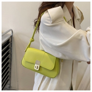 Detail of neon green leather shoulder bag with metal lock buckle and knotted strap detail