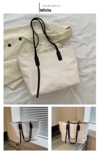 Macro detail of the white quilted leather texture and zipper on the large tote bag