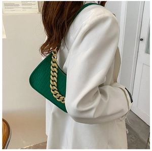 Detail of green crocodile texture shoulder bag with decorative thick gold chain strap