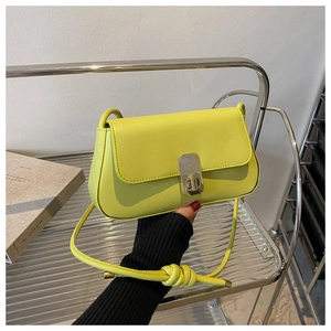 Close-up of lemon yellow square crossbody bag with metallic clasp and knotted strap