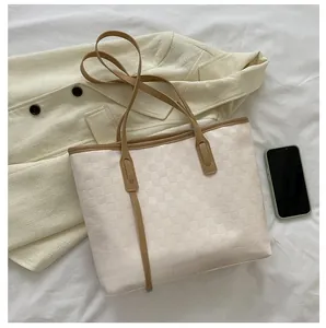 Top-down view of a textured tote bag with leather handles next to a smartphone