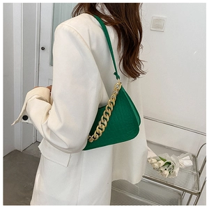 Detail of green faux crocodile skin shoulder bag with decorative thick gold chain strap