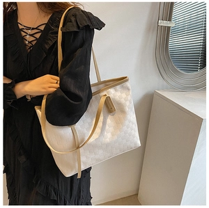 Minimalist beige tote bag with checkered texture worn by a model in a black dress