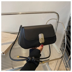 Detail of a black matte leather flap bag featuring a vertical gold metal twist lock