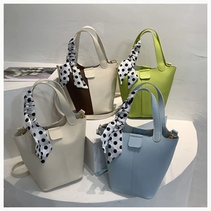 Detailed view of four stylish bucket bags with decorative polka dot silk scarves on handles