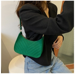 Detail of emerald green quilted crescent bag with V-shaped stitching and gold zipper