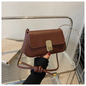 Detail of vintage brown leather crossbody bag with a golden textured twist lock