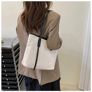 Close-up of cream checkerboard tote bag with black leather straps on a model