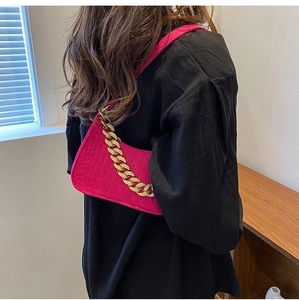 Close-up of pink faux leather underarm bag featuring crocodile pattern and gold chain