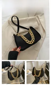 Close-up of black crocodile pattern baguette bag with chunky gold chain detail