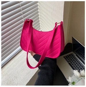 Detail of fuchsia textured felt crescent bag with V-shaped quilting held in soft lighting