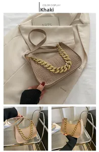 Close-up of khaki crocodile pattern handbag featuring a chunky gold chain strap