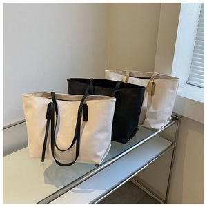 Close-up of three large PU leather tote bags featuring elegant quilted textures on a glass shelf