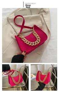 Detail of rose red crocodile pattern underarm bag with decorative gold metal chain strap