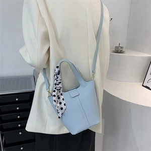 Minimalist light blue bucket bag with polka dot scarf and golden metal hardware