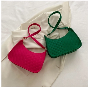 Close-up of V-quilted felt hobo bags in vibrant pink and green with gold hardware