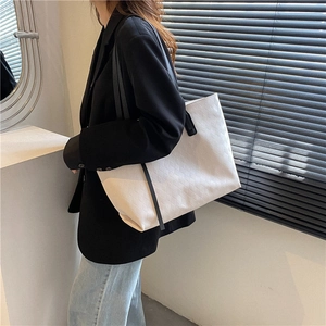 Women's large capacity cream woven tote bag with black handles in professional office setting