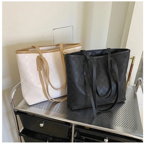 Detail of large tote bags with checkered embossing in cream and black on a metal cart