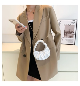 Detail of white pleated cloud bag with elegant gold chain strap worn with a blazer