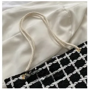 Detail of checkered woven tote bag showing white rope handles and gold grommets