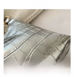 Close-up of silver crocodile embossed handbag with premium golden metal hardware detail