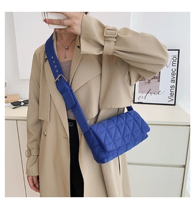 Close-up of a dark blue quilted crossbody bag featuring a soft puffer grid design