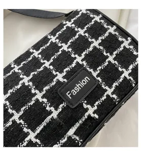 Dettaglio del tessuto in tweed bianco e nero e toppa in pelle 'Fashion' sulla borsa