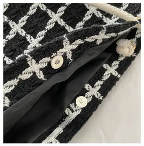 Detail view of black and white tweed tote bag with silver magnetic snap closure