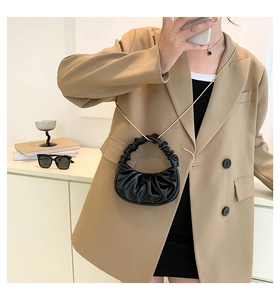 Detail of black pleated cloud bag with gold chain strap and stylish gathered handle