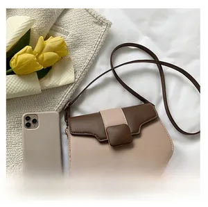 Detail of color-block square crossbody bag with brown buckle on a soft white background